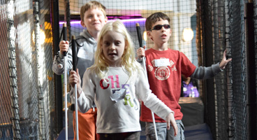 Three blind kids walk confidently with their canes through an obstacle course.